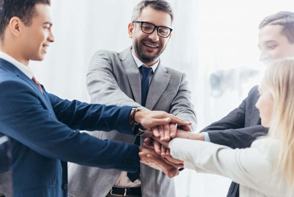 happy business team stacking hands in office